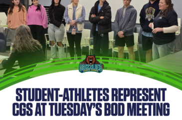 A group of Clover Garden School student-athletes stand at the front of a meeting room as a coach speaks to the Board of Directors.